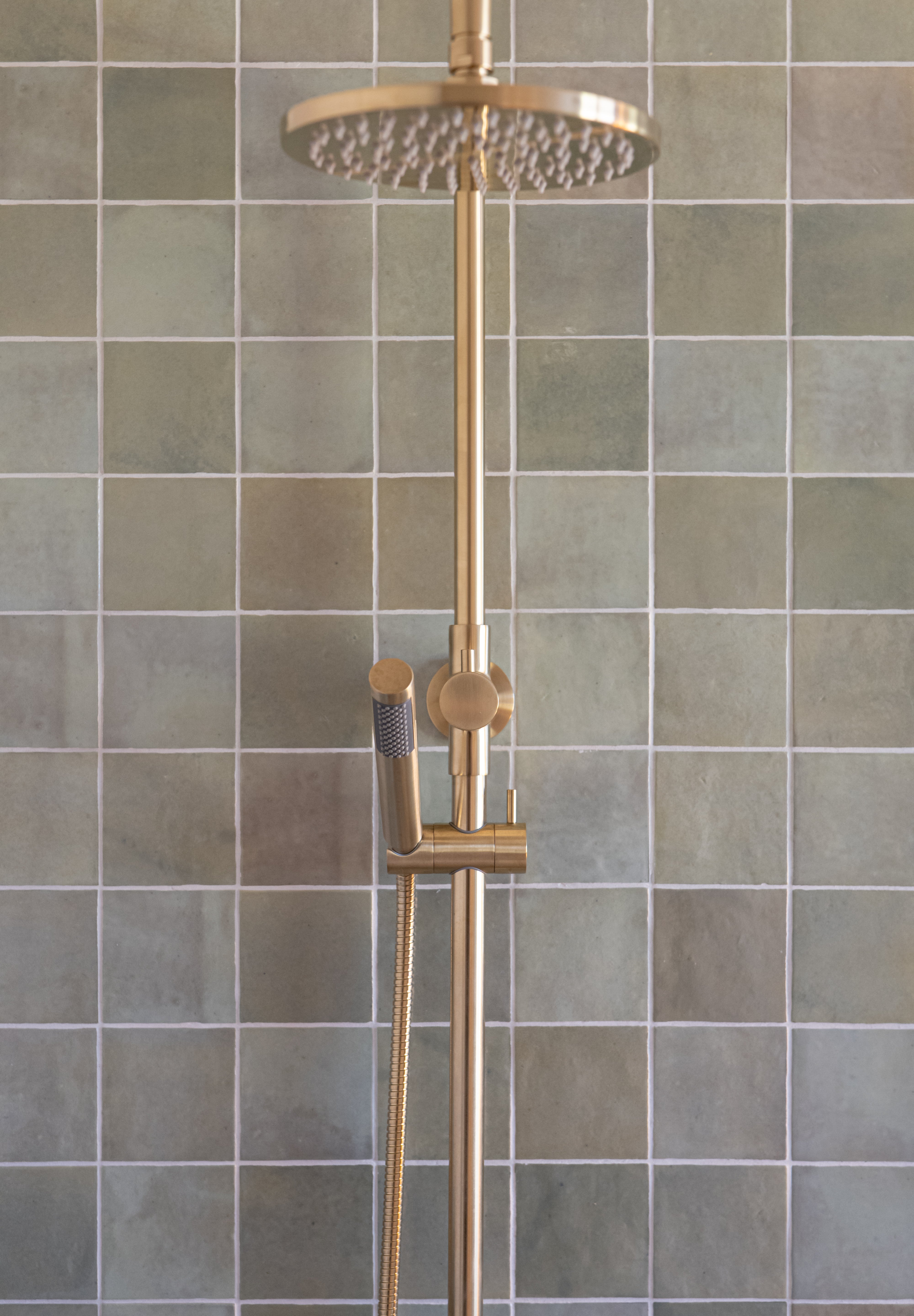 brushed gold twin round combination shower rail with diverter on a green feature tile background