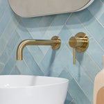 a brushed gold wall spout and mixer wall mounted on a blue tile backgroud