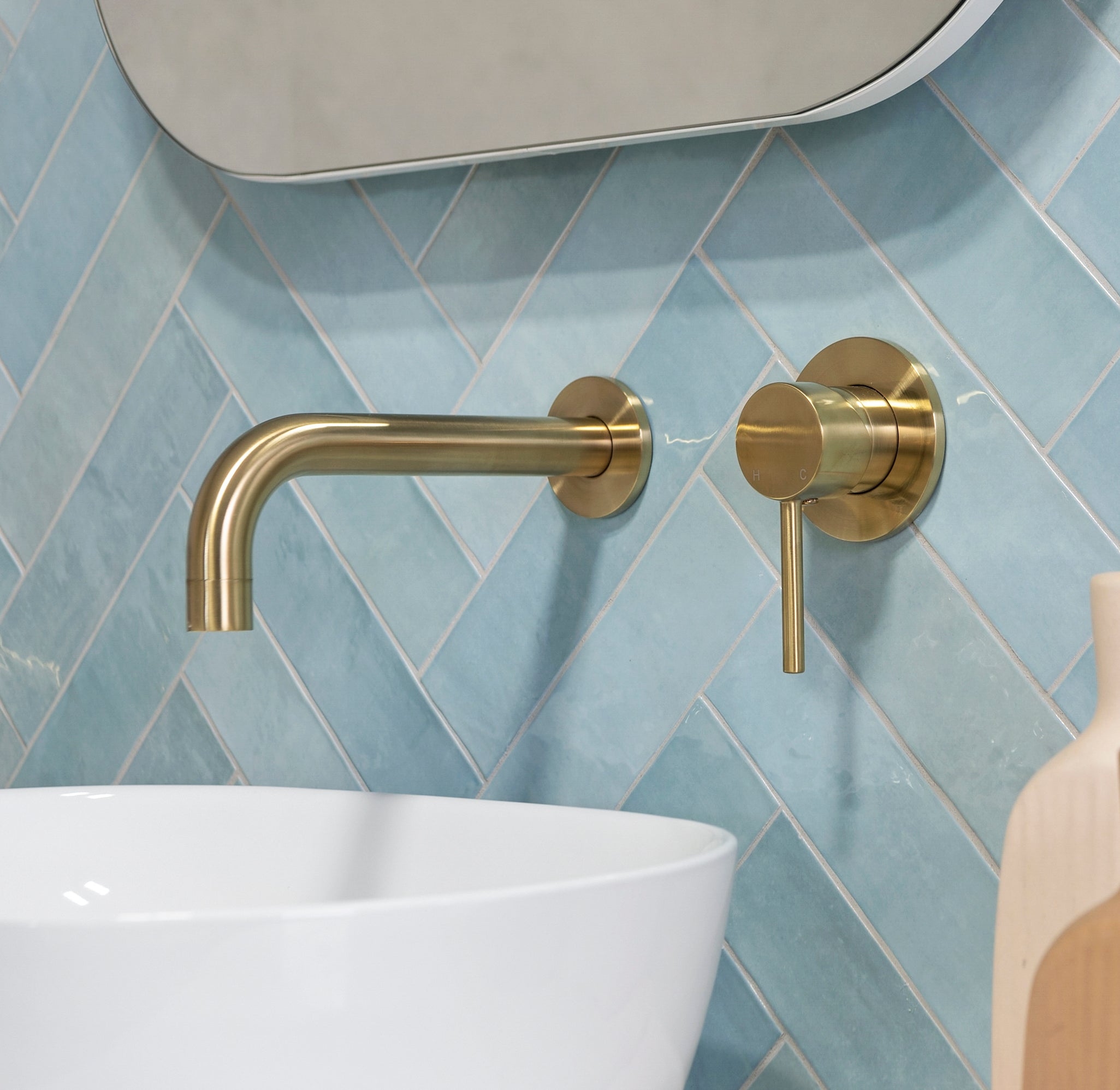 a brushed gold wall spout and mixer wall mounted on a blue tile backgroud
