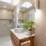 Brushed nickel bathroom fixtures in a modern bathroom with shower, sink, and decorative elements.