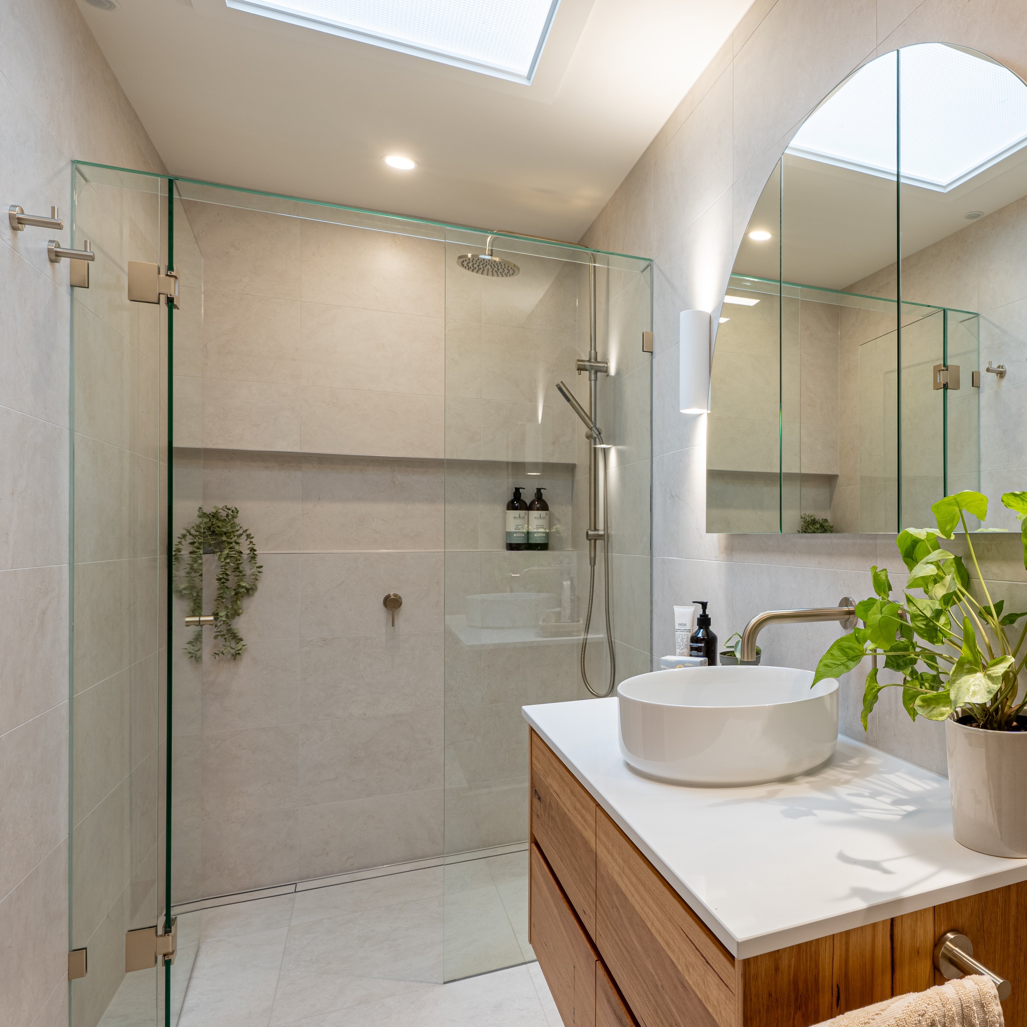 Brushed nickel bathroom fixtures in a modern bathroom with shower, sink, and decorative elements.