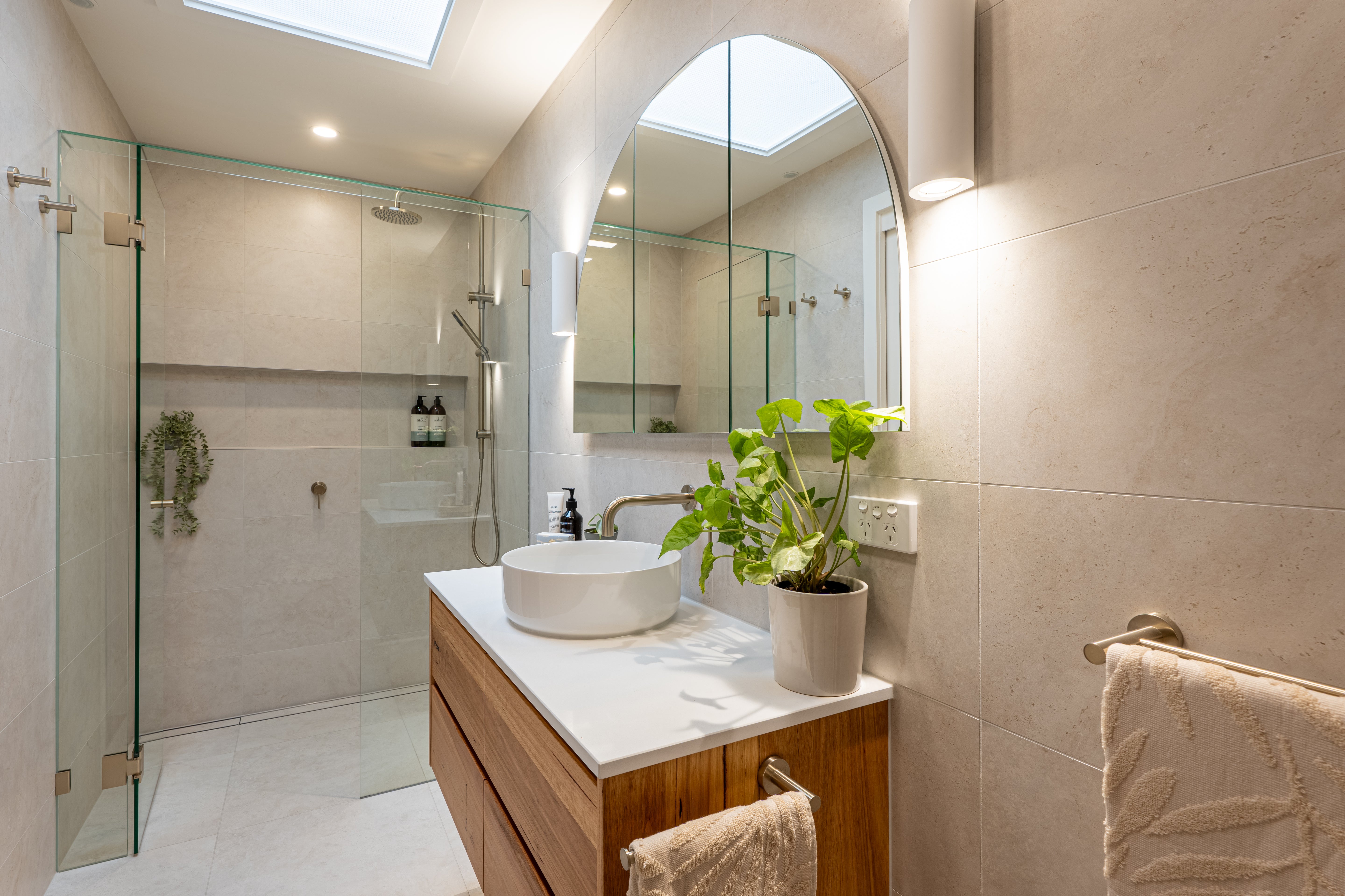 Brushed nickel bathroom fixtures in a modern bathroom with shower, sink, and decorative elements.