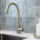 a brushed nickel kitchen laundry mixer on a white bench with a blue tile background