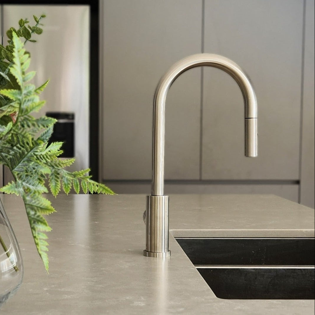 a brushed nickel kitchen laundry pull out mixer tap on a modern kitchen countertop with a vase of flowers