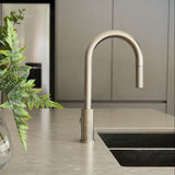 a brushed nickel kitchen laundry pull out mixer tap on a modern kitchen countertop with a vase of flowers