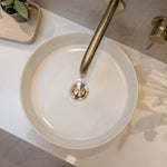 White round sink with a brushed nickel pop up waste with no overflow t on a light-colored countertop.