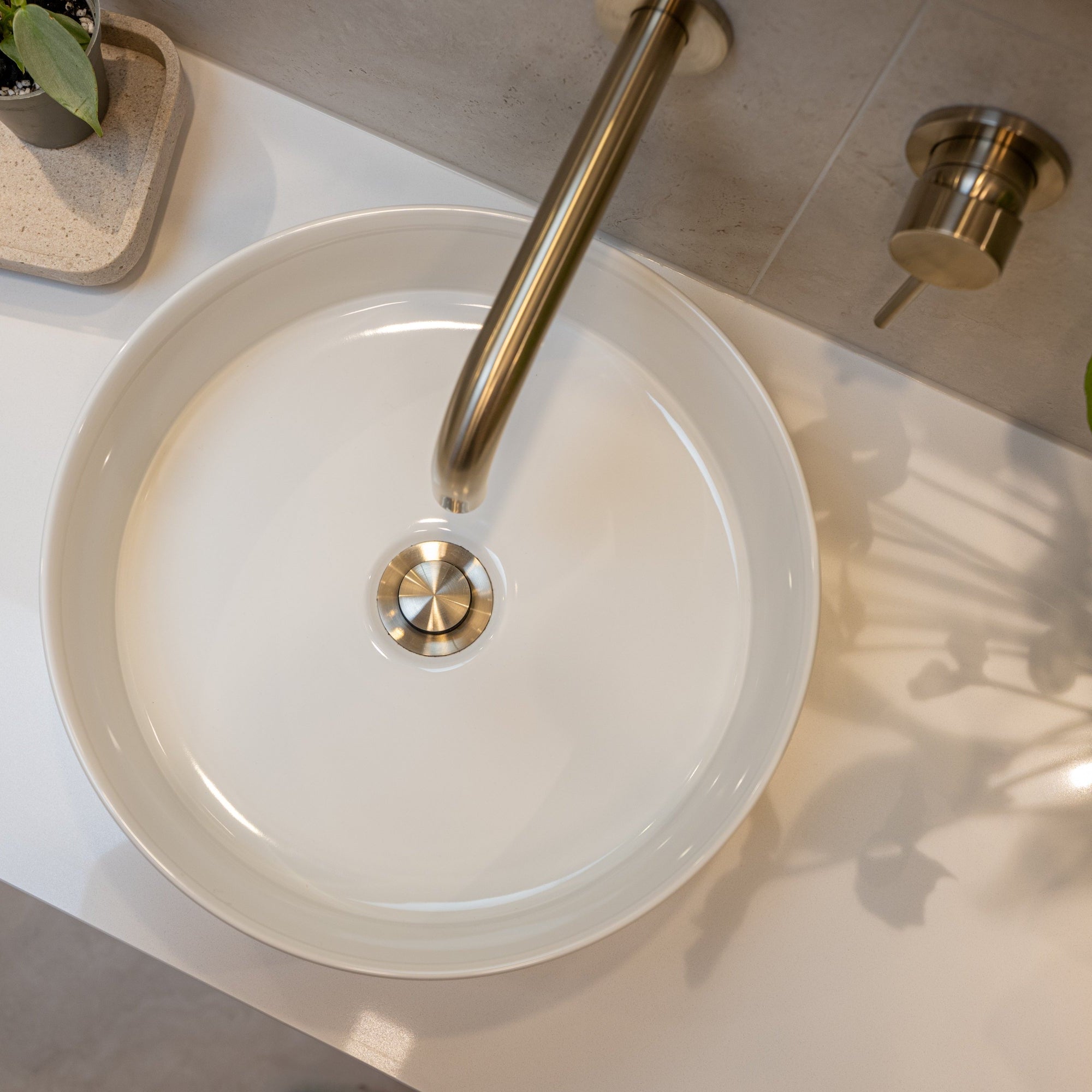 White round sink with a brushed nickel pop up waste with no overflow t on a light-colored countertop.