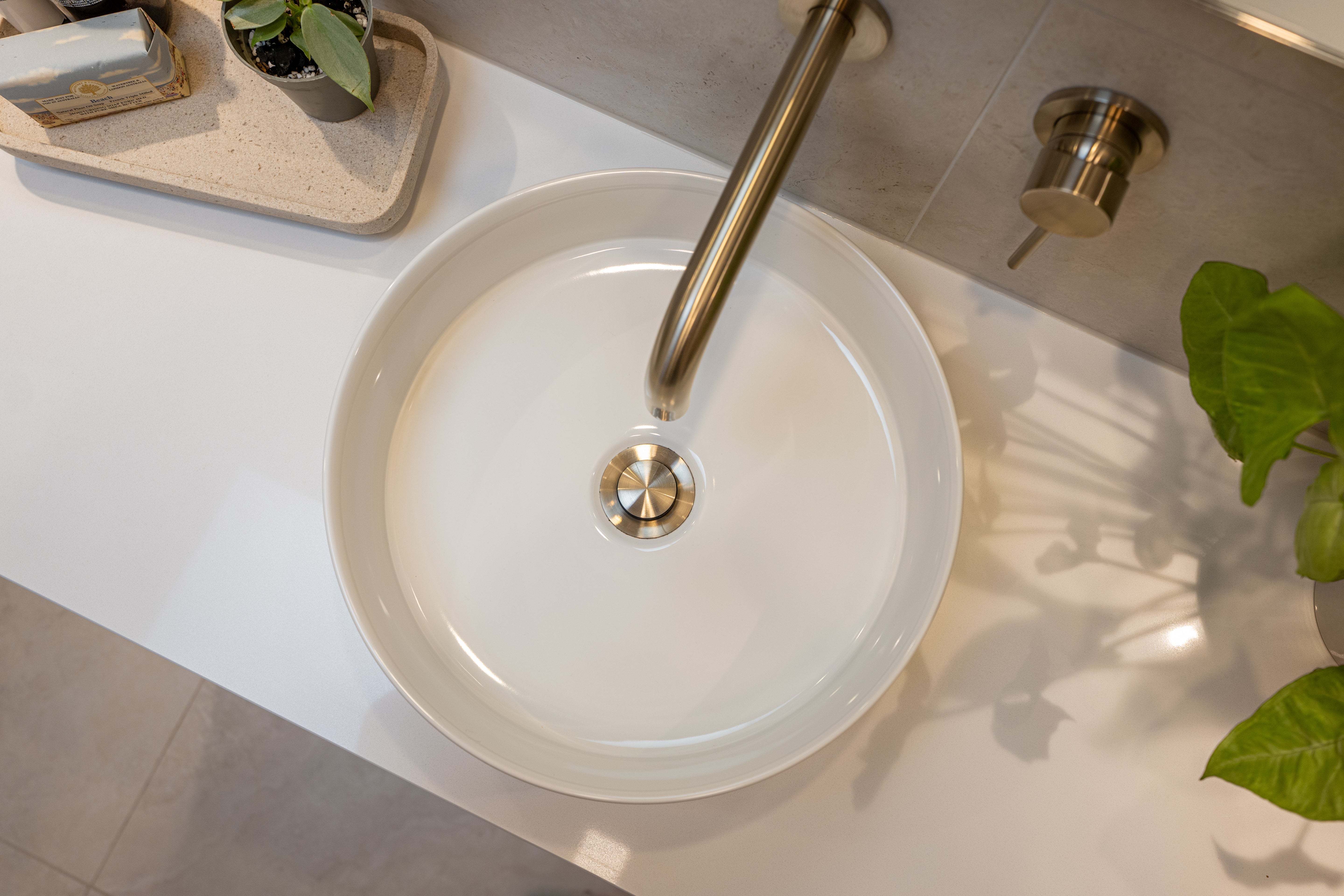 White round sink with a brushed nickel pop up waste with no overflow t on a light-colored countertop.