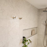 Shower area with tiled walls, a brushed nickel twin shower and diverter, brushed nickel robe hooks with a niche.