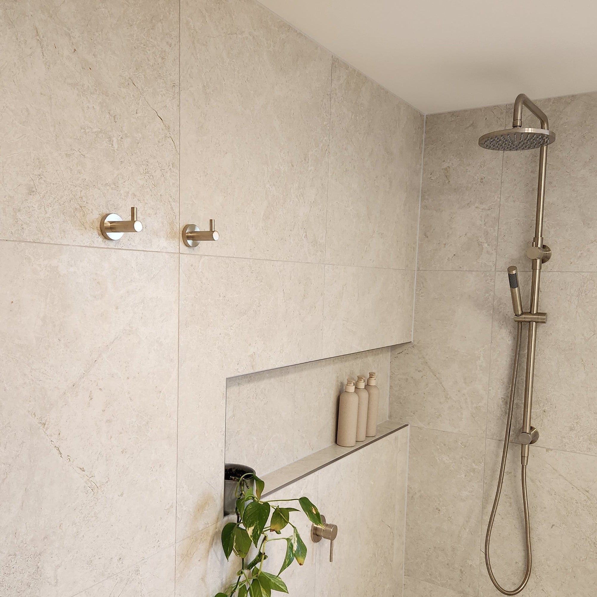 Shower area with tiled walls, a brushed nickel twin shower and diverter, brushed nickel robe hooks with a niche.