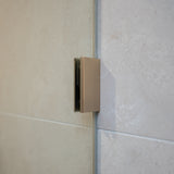 Brushed nickel shower glass clamp on a tiled wall.