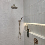 a brushed nickel shower handpiece on a bracket wall mounted on a tiled bathroom wall