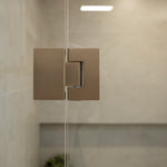 Brushed nickel shower glass hinge with glass shower  and tiled wall.