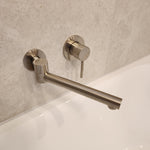 Brushed nickel swivel bath spout on a tiled wall next to a brushed nickel mixer
