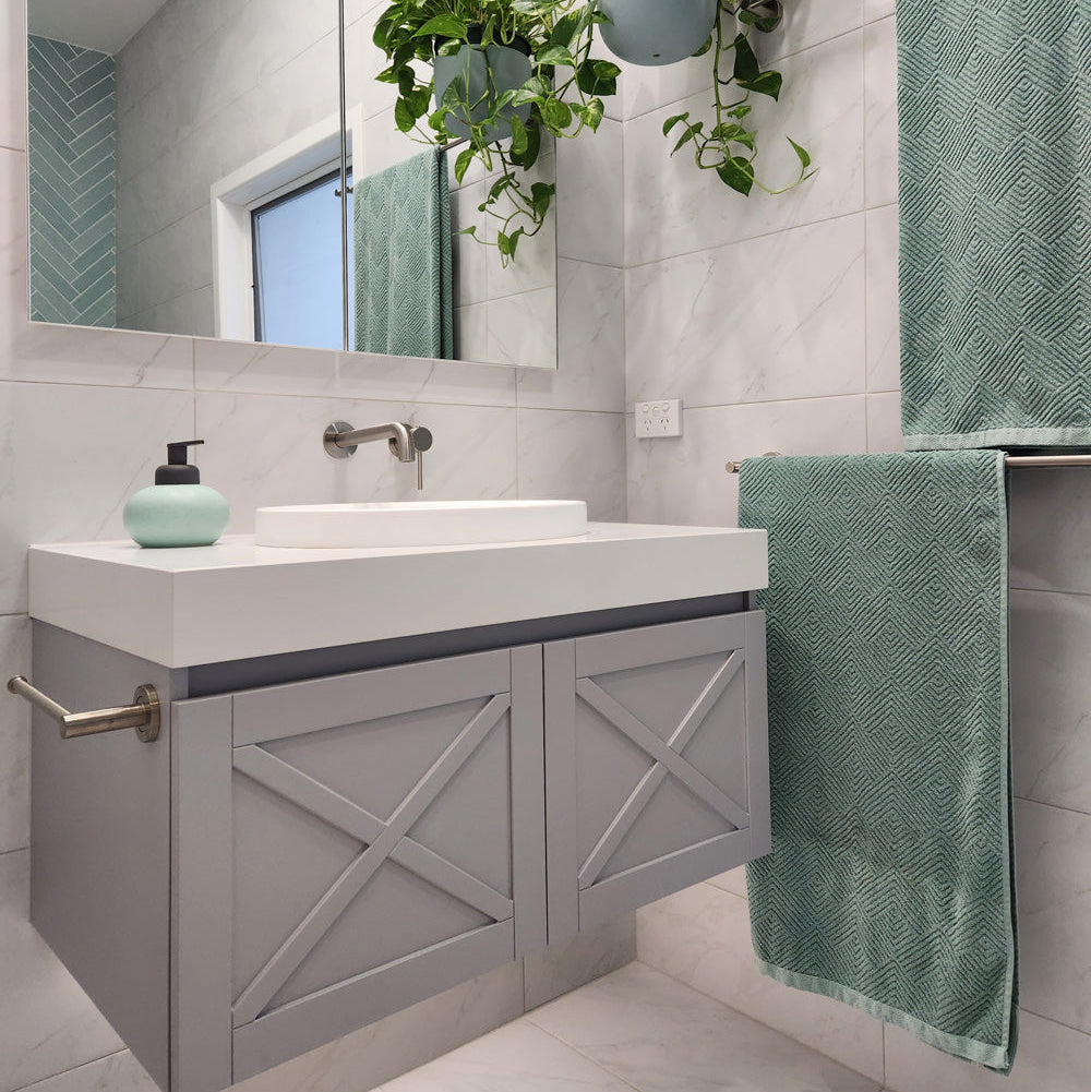 a brushed nickel towel holder mounted on a grey vanity with white stone top