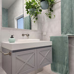 a brushed nickel towel holder mounted on a grey vanity with white stone top