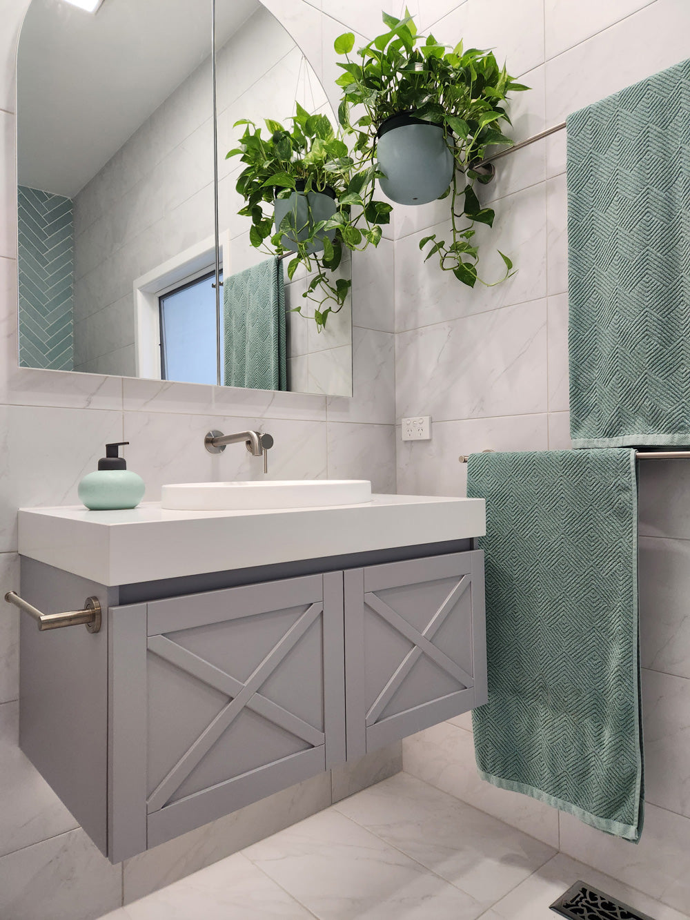a brushed nickel towel holder mounted on a grey vanity with white stone top