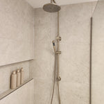 Brushed nickel twin shower with diverter on a tiled bathroom wall
