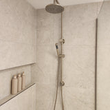 Brushed nickel twin shower with diverter on a tiled bathroom wall