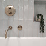 a brushed nickel wall mixer with diverter on a light blue tiled background