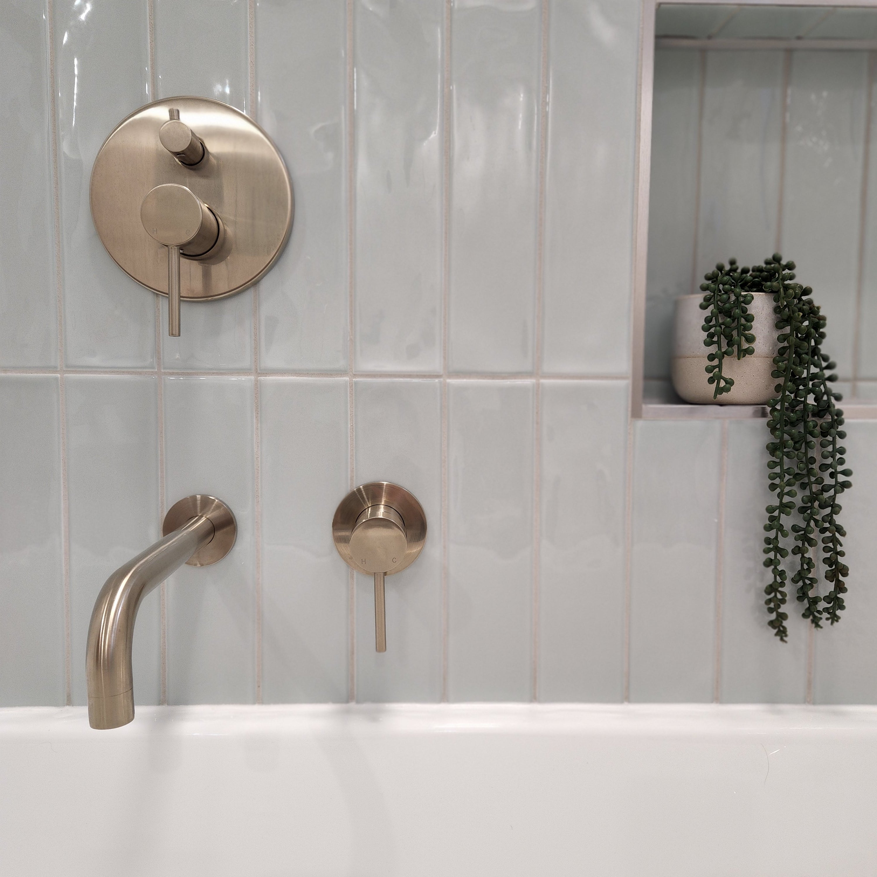 a brushed nickel wall mixer with diverter on a light blue tiled background