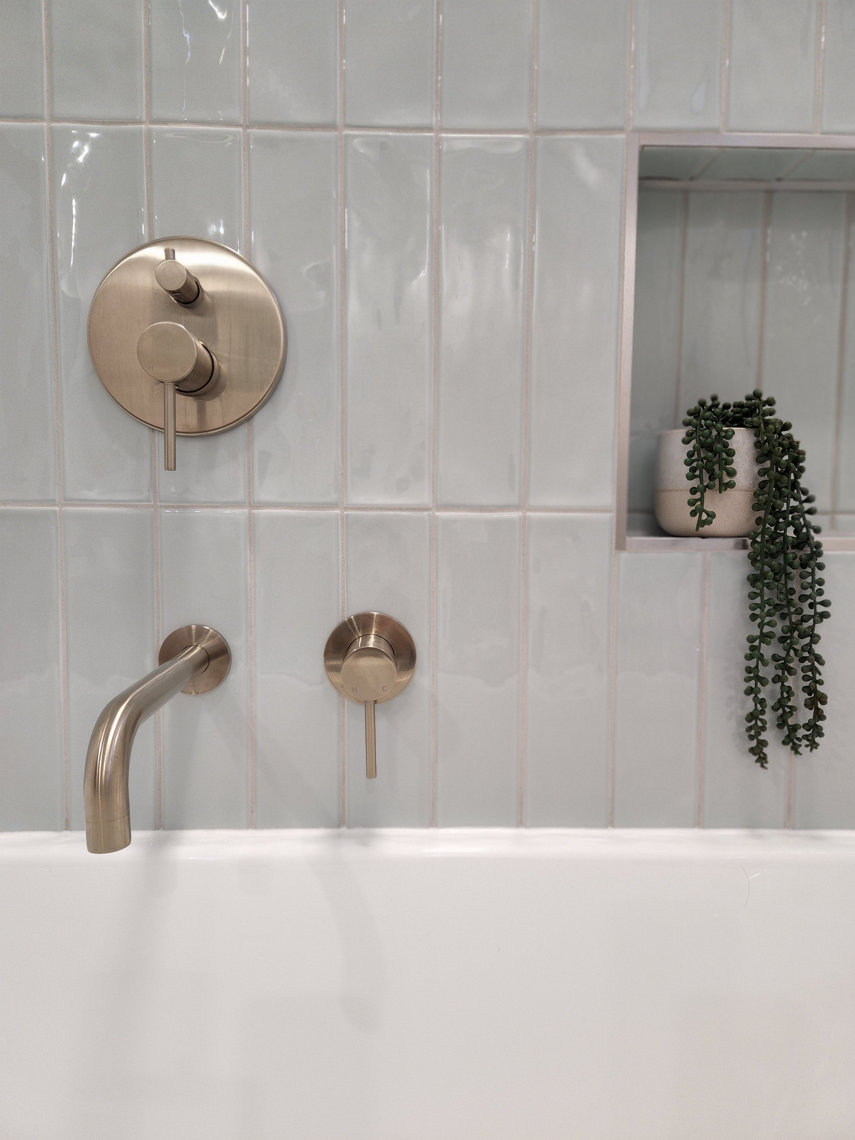 a brushed nickel wall mixer with diverter on a light blue tiled background