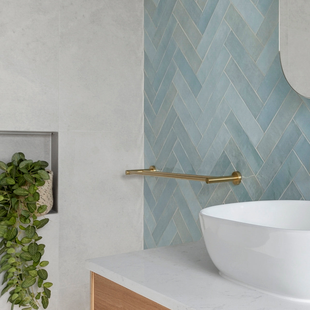 brushed gold single towel rail in a bathroom wall mounted to a blue tiled wall 