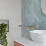 brushed gold single towel rail in a bathroom wall mounted to a blue tiled wall 