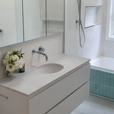 Modern bathroom with chrome towel holder, spout and mixer with a white vanity, sink, and bathtub.