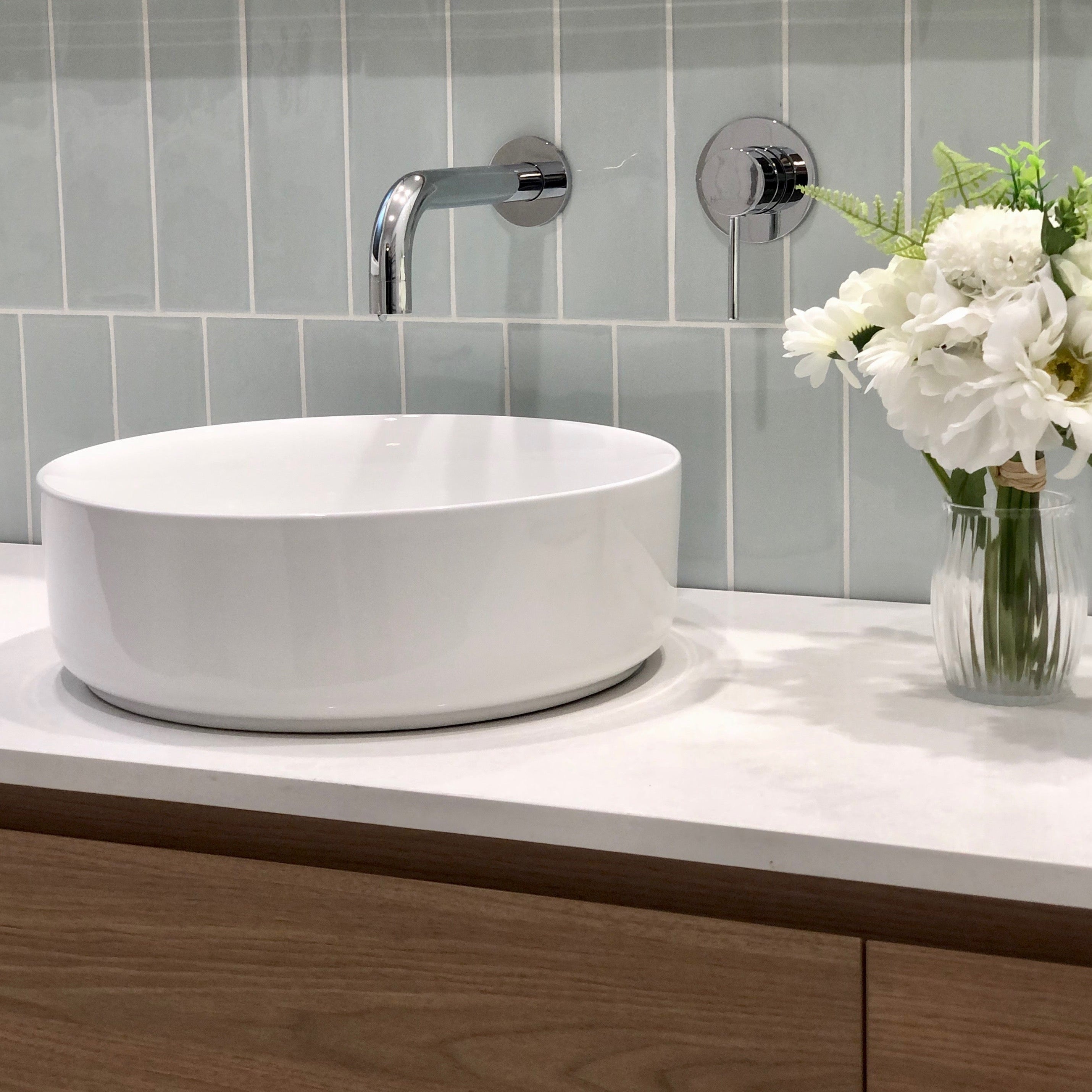 a chrome wall mixer and spout on a blue tile background