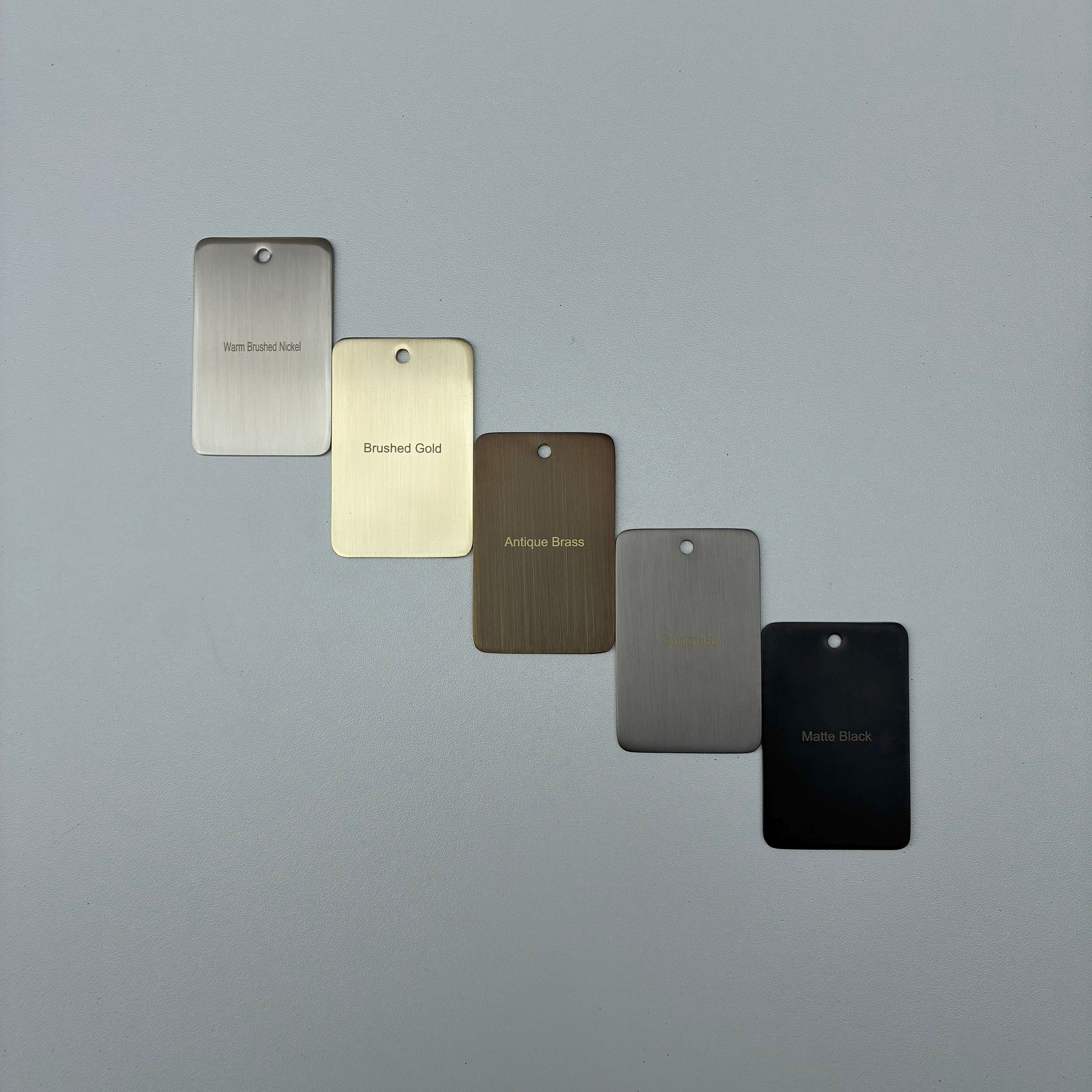 Five metal color samples labeled 'Warm Brushed Nickel', 'Brushed Gold', 'Antique Brass', 'Gun Metal', and 'Matt Black' on a grey background.