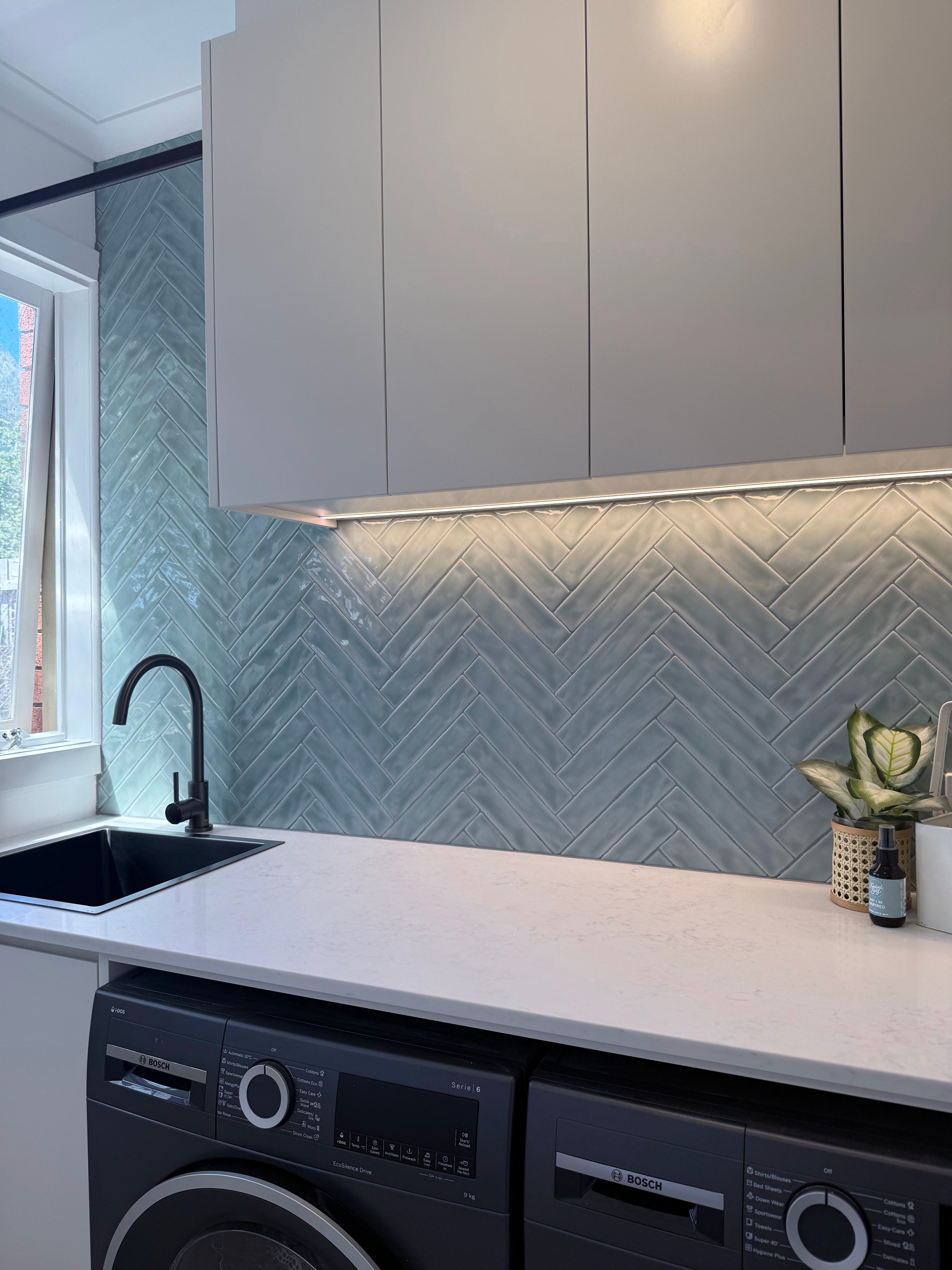 Modern Laundry with white cabinets, a chevron-patterned backsplash, and with a gun metal kitchen/laundry mixer