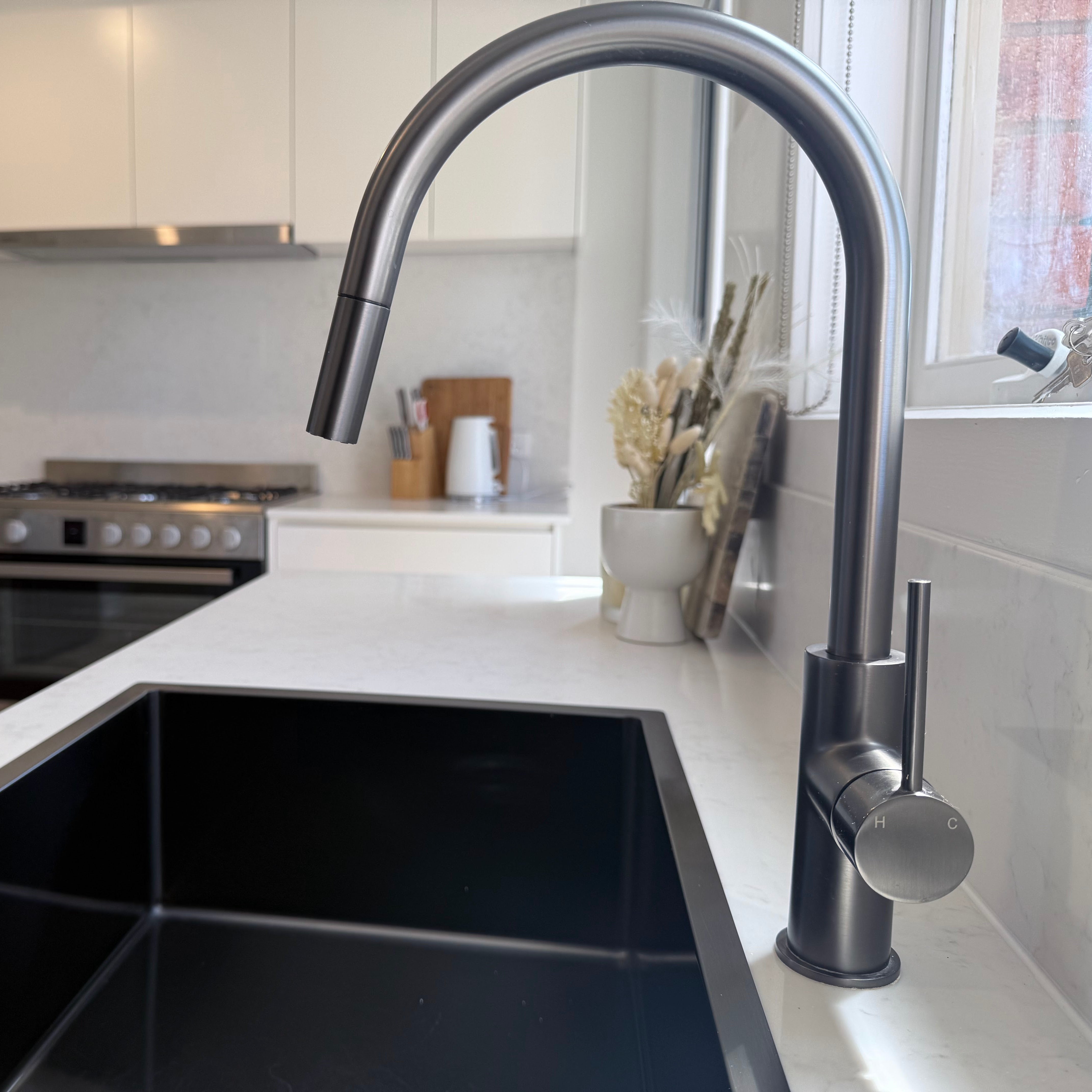 Modern kitchen with a gun metal sink and gun metal pull out kitchen/laundry mixer.