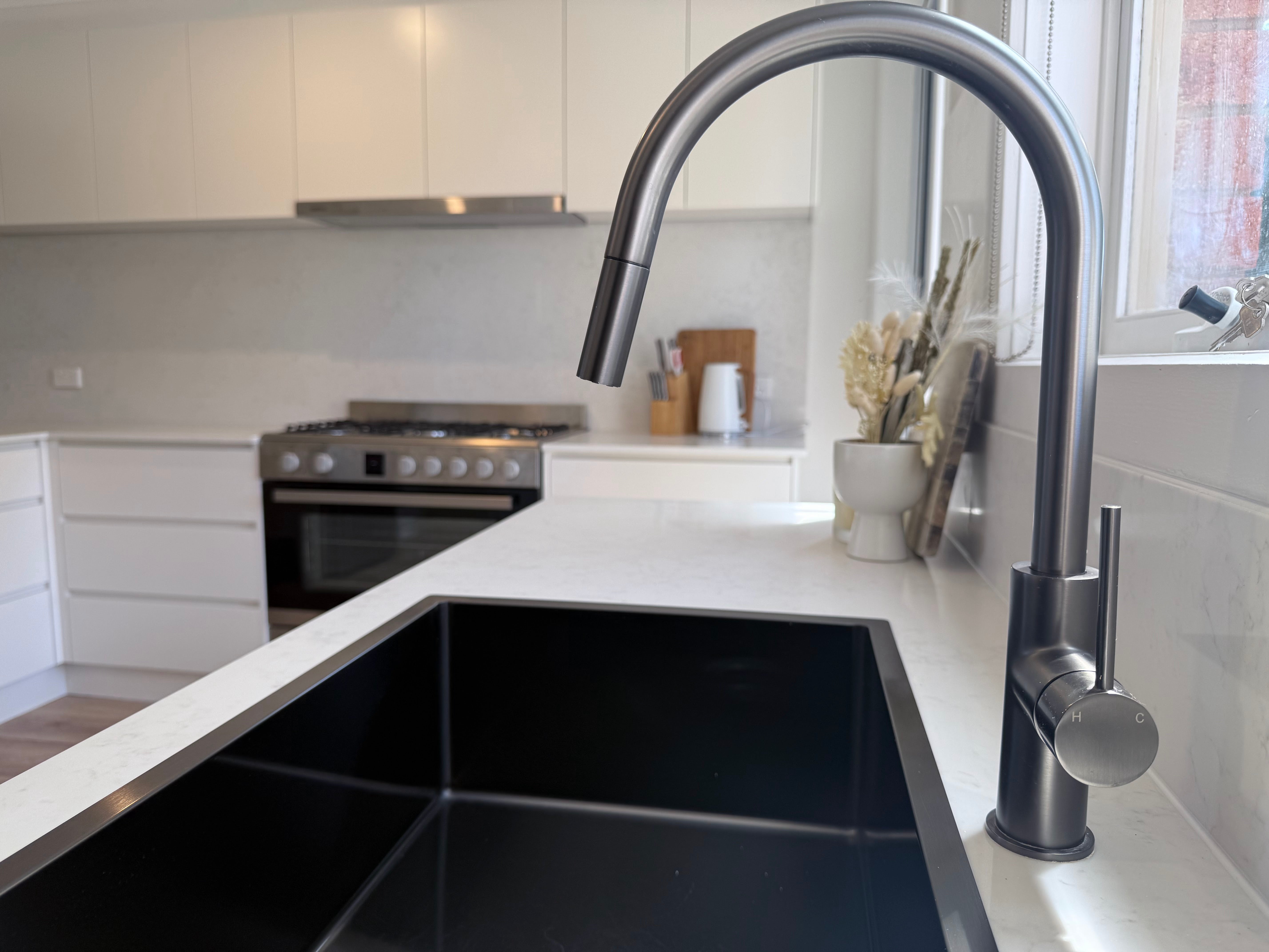 Modern kitchen with a gun metal sink and gun metal pull out kitchen/laundry mixer.