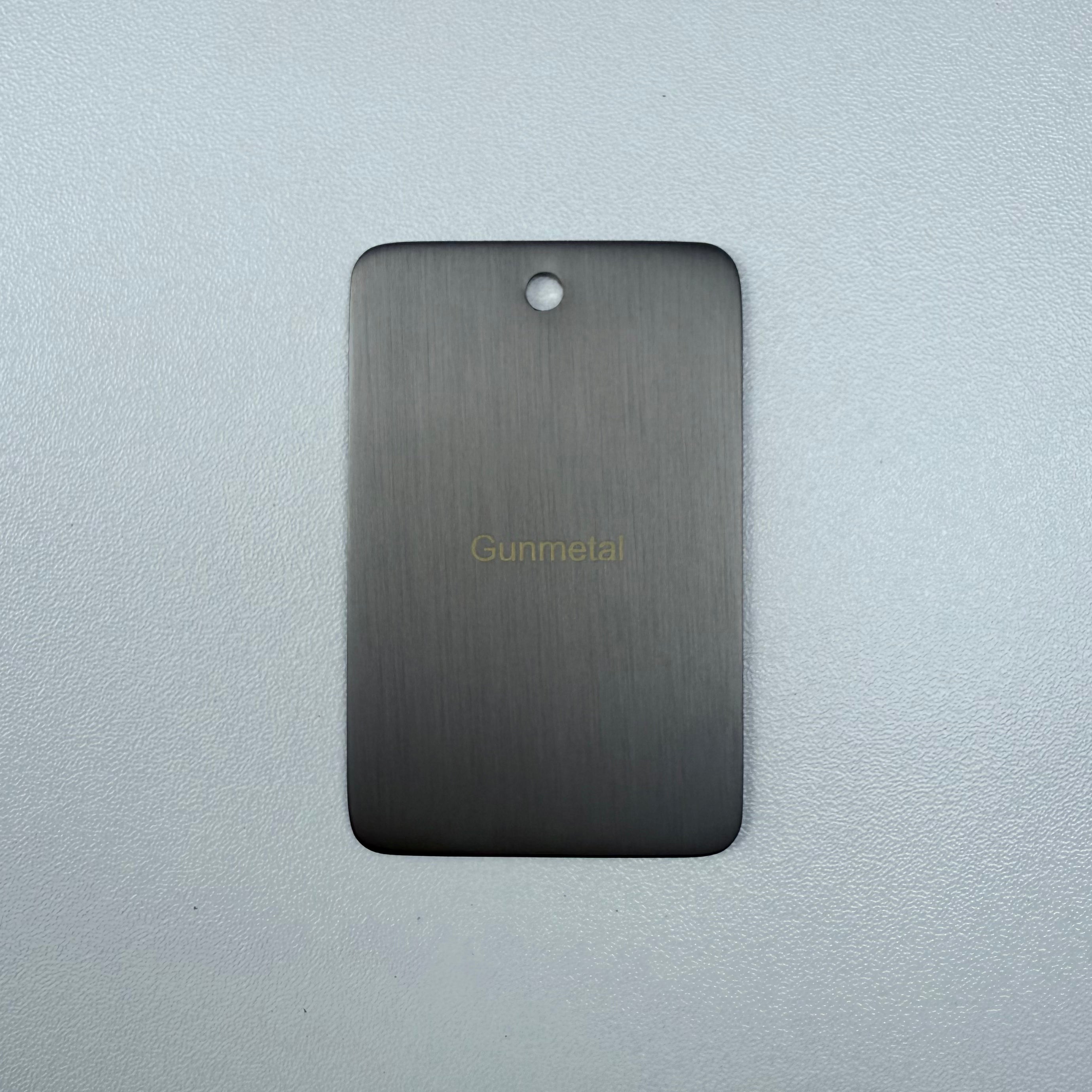 Gun metal sample disc on a grey background