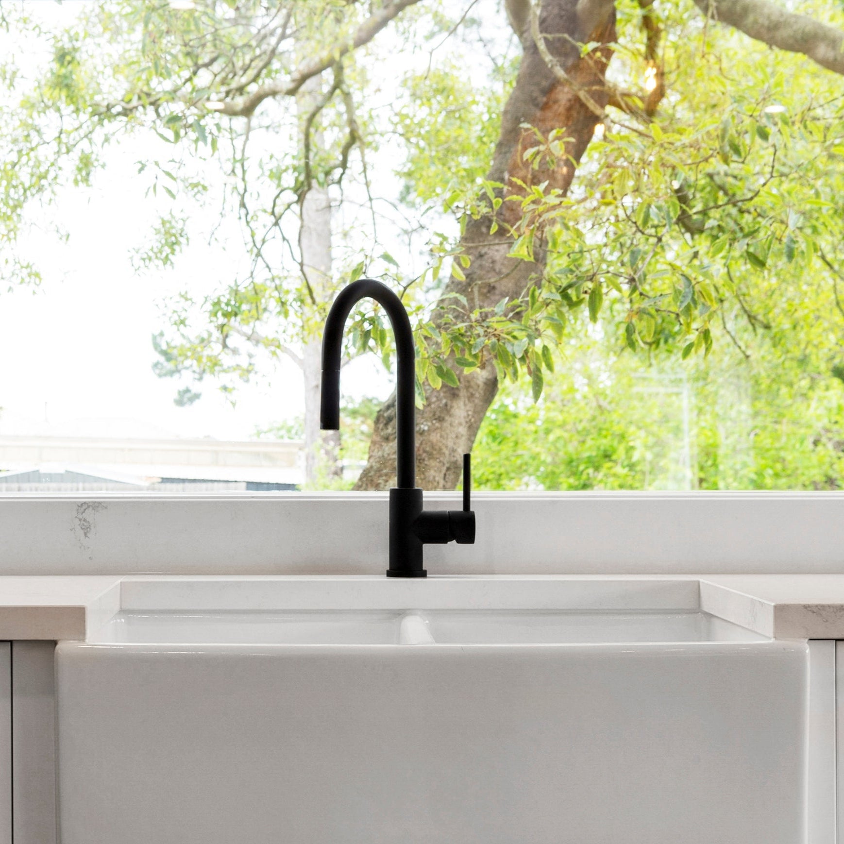 a matt black kitchen laundry pull out mixer tap in a bright kitchen setting
