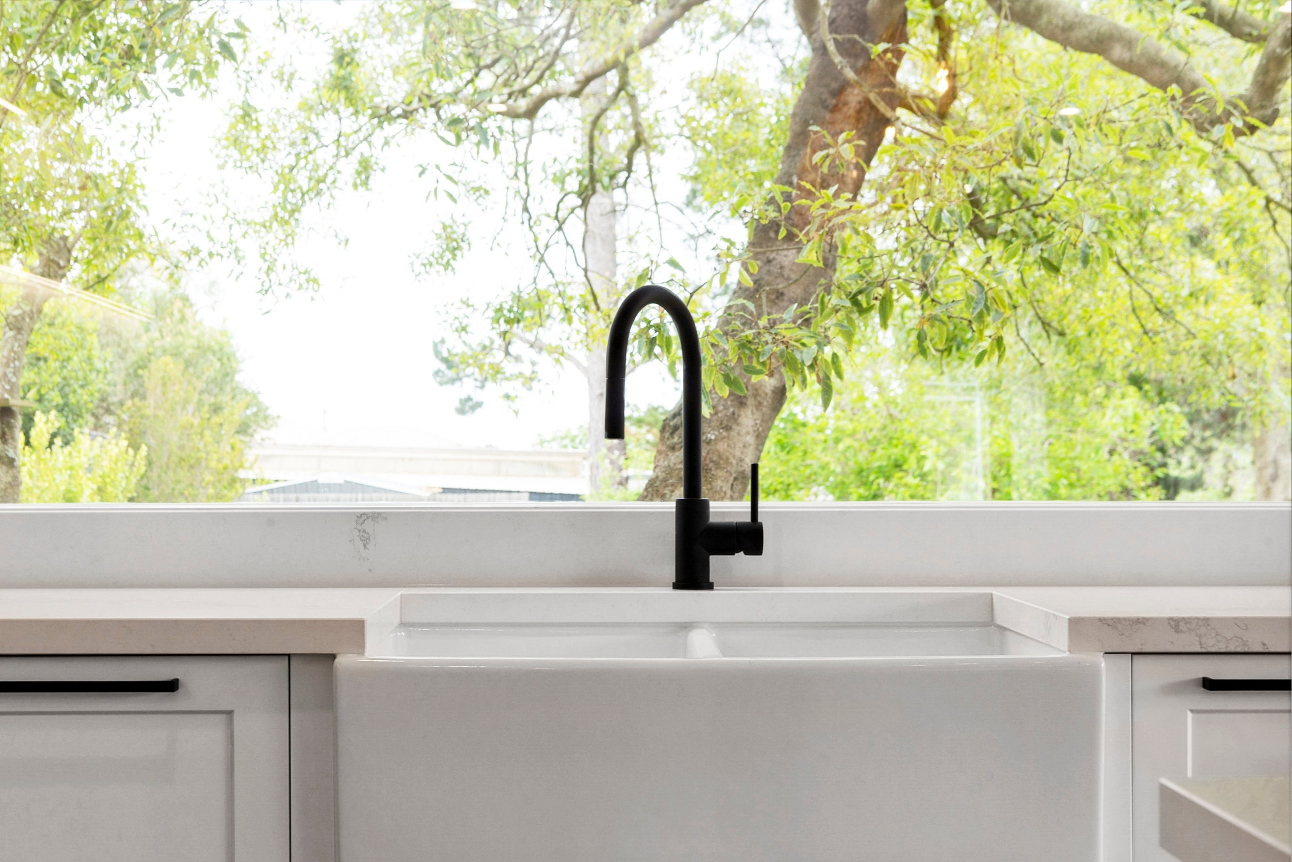 a matt black kitchen laundry pull out mixer tap in a bright kitchen setting