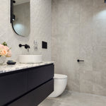 an matt black toilet roll holder in a modern bathroom with black vanity, white sink, and toilet.