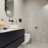 an matt black toilet roll holder in a modern bathroom with black vanity, white sink, and toilet.